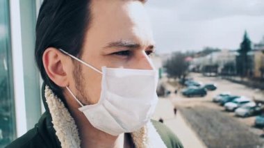 COVID-19 Coronavirus salgınına karşı korunmak için tıbbi solunum maskesi takmış bir adamla karşı karşıyayız.