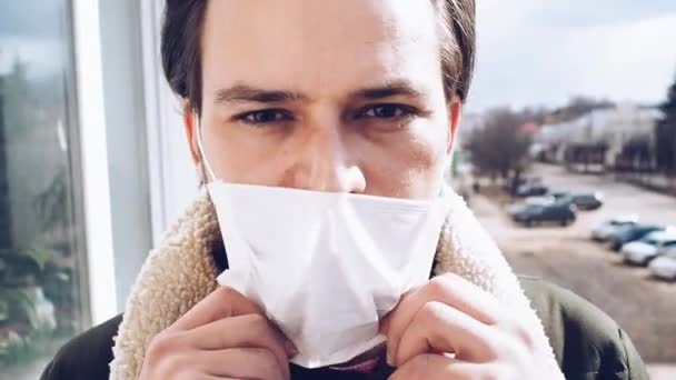 Mens verwijdert een medisch ademhalingsmasker ter bescherming tegen de COVID-19 coronavirus epidemie — Stockvideo