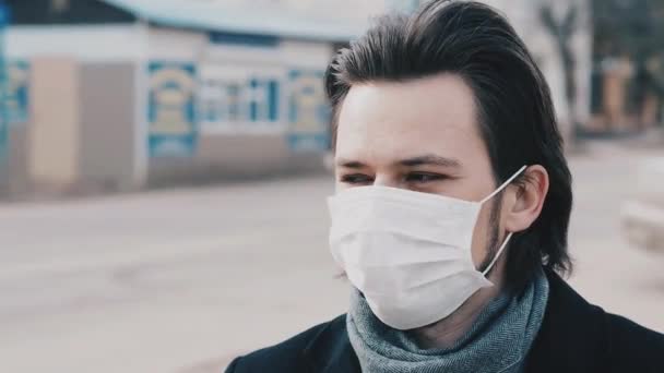 Белый европеец в респираторной медицинской маске для защиты от коронавируса COVID-19 на улице — стоковое видео