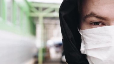 COVID-19 koronavirüs salgınına karşı korunmak için solunum maskesi takan bir genç.