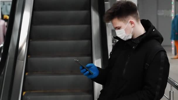 Begreppet coronavirusepidemin COVID-19. Tonåring i medicinsk mask för att skydda mot 2019-ncov-pandemin använder mobiltelefon — Stockvideo