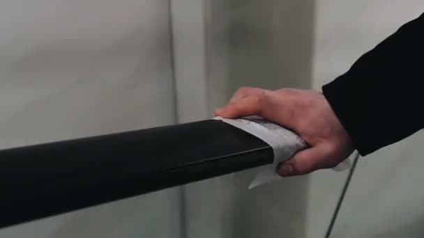 Die Hand eines Mannes mit einer Serviette zum Schutz vor der COVID-19 Coronavirus-Epidemie bewegt sich auf einem Geländer — Stockvideo