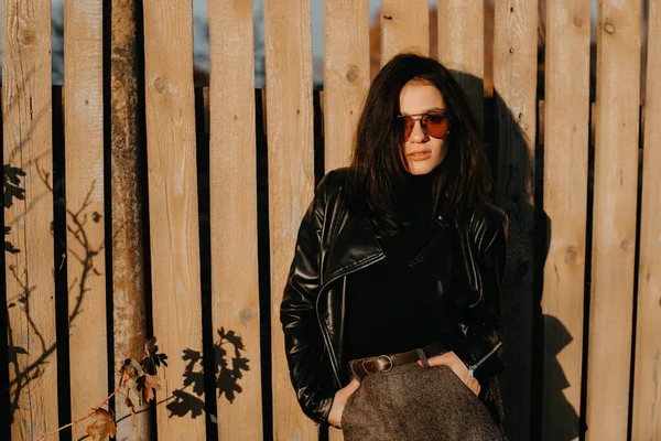 Young brunette girl in a leather jacket and shorts in sunglasses on style — Stock Photo, Image