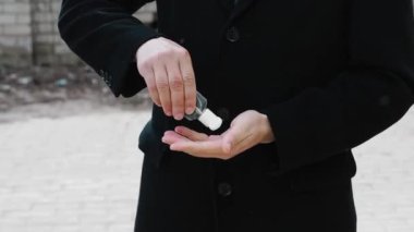Adam koronavirüsten korunmak için sokakta ellerini antiseptik sıvı sabunla yıkıyor.
