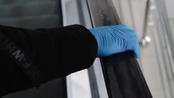 VICHUGA, RUSSLAND - 22. MÄRZ 2020: Mann legt Handschuh zum Schutz gegen Coronavirus COVID-19 am Geländer einer Rolltreppe an — Stockvideo