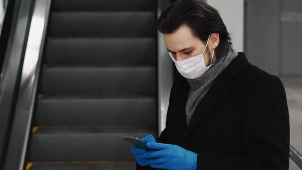 Άνδρας που φοράει ιατρική μάσκα και γάντια για την προστασία από την επιδημία COVID-19 coronavirus χρησιμοποιεί κινητό τηλέφωνο — Αρχείο Βίντεο