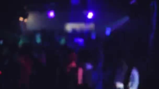 Multitud de personas bailando en la pista de baile de un club nocturno bajo la luz de focos de colores y láseres — Vídeos de Stock