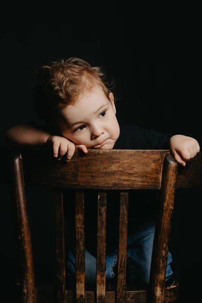Egy komoly, átgondolt kaukázusi gyermek portréja egy fiú a széken — Stock Fotó