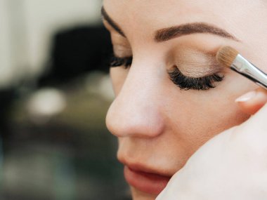 Bir makyaj sanatçısının ellerinde bir kadının gözlerinde göz farı ile fırçalamak.