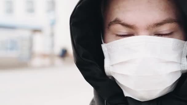 Epidemic is the COVID-19 coronavirus pandemic. Young man in a medical respiratory mask opens eyes — Stock Video