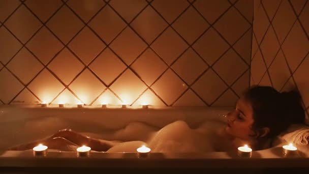 Gyönyörű fiatal barna lány a fürdőszobában élvezi és mozog a lábát a hab — Stock videók