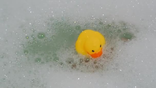 Handen håller en gummigul anka ur vattnet i ett bad med skum — Stockvideo
