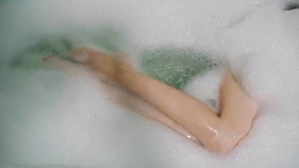 Menina move seu esbelto belas pernas no banho com espuma — Vídeo de Stock