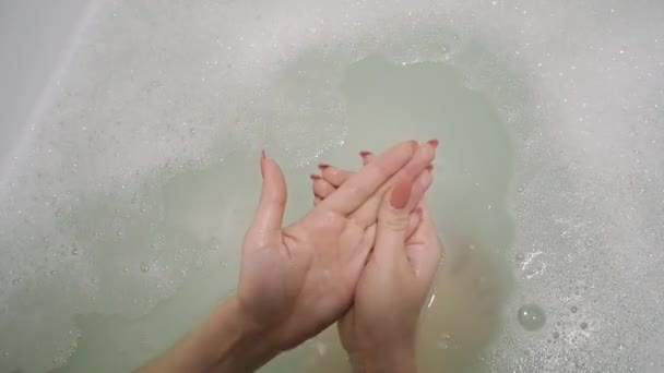 Девушка массирует и моет руки в ванне пеной — стоковое видео