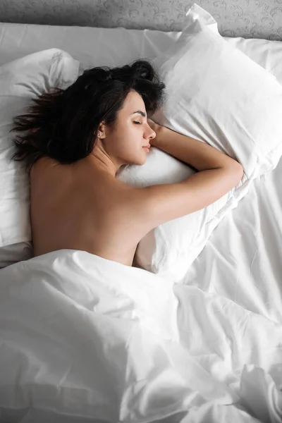 Hermosa chica joven sexy durmiendo en una almohada debajo de una manta blanca en la cama — Foto de Stock