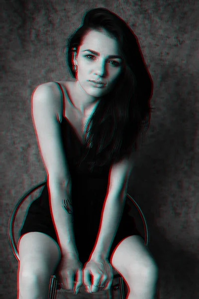 Retrato de uma jovem menina atraente em um vestido preto sentado em uma cadeira — Fotografia de Stock