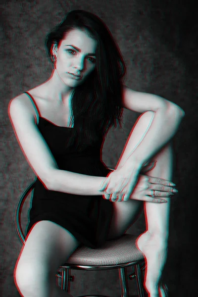 Retrato de uma jovem menina atraente em um vestido preto sentado em uma cadeira — Fotografia de Stock