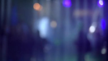 Bir gece kulübünün dans pistinde renkli spot ışıkları ve lazerlerin altında dans eden kalabalık.