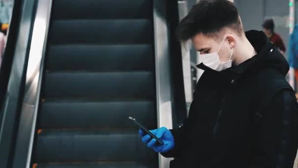 Concepto de la epidemia de coronavirus COVID-19. Adolescente en una máscara médica para protegerse contra la pandemia de 2019-ncov utiliza un teléfono móvil — Vídeo de stock