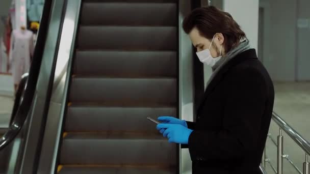 COVID-19コロナウイルス流行から守るために呼吸器医療用マスクと手袋を身に着けている男は携帯電話を使用しています — ストック動画