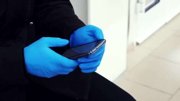 Людина з рукавичками використовує мобільний телефон. Концепція коронавірусу COVID-19 — стокове відео