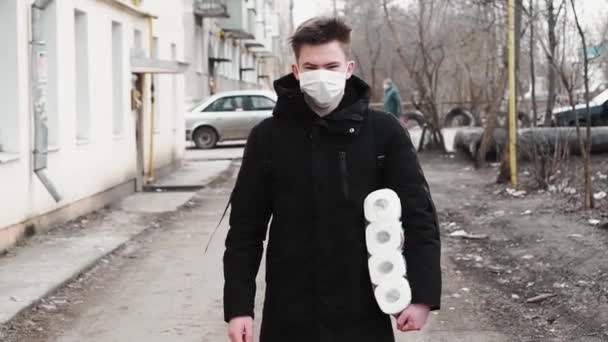 ロシア,ビチュガ- 2020年3月22日:COVID-19検疫中にトイレペーパーを供給してコロナウイルスから保護するために医療用マスクを着用した男 — ストック動画