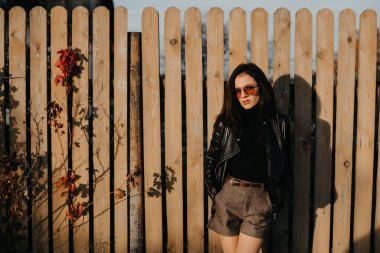 Deri ceketli, güneş gözlüklü, esmer, genç bir kız.