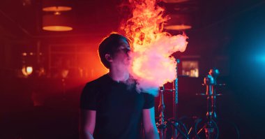 Adam dinleniyor ve nargile tüttürüyor. Dinlenme odasında duman üflüyor.