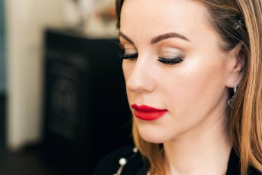 Profesyonel makyajlı, uzun kirpikli ve kırmızı rujlu bir kadın yüzü.