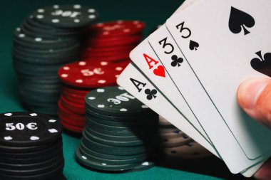 Oyun çiplerinin arka planında poker oynayan oyuncunun elinde iki çift kart var.