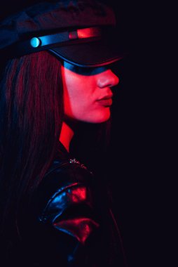 Kırmızı ışıklı deri şapkalı ve ceketli bir kızın moda portresi.