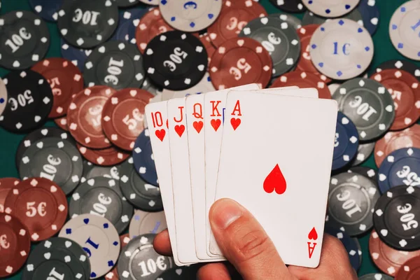 Royal flush in de handen van de speler op de achtergrond van spel chips — Stockfoto