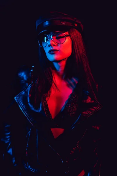 Fashion portrait of a sexy girl with glasses in a leather jacket and cap — Stock Photo, Image