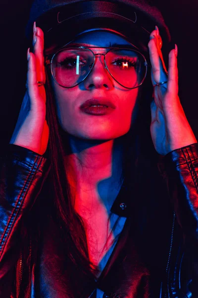 Fashion portrait of a stylish sexy girl with glasses in a leather jacket and a cap — Stock Photo, Image