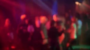 Bir gece kulübünün dans pistinde renkli spot ışıkları ve lazerlerin altında dans eden kalabalık.