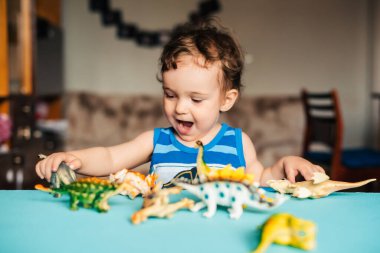 Evde oyuncak dinozorlarla oynayan tatlı bir çocuk.
