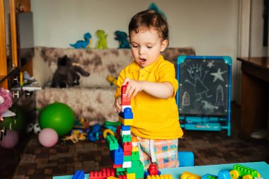 Mutlu çocuk evde renkli bloklarla oynuyor.