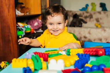 Mutlu çocuk evde renkli bloklarla oynuyor.