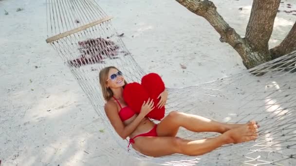 Mulher em rede na praia tropical na ilha Samui, Tailândia. Menina yuong bonita que estabelece com brinquedo na praia. Biquíni vermelho e óculos de sol . — Vídeo de Stock