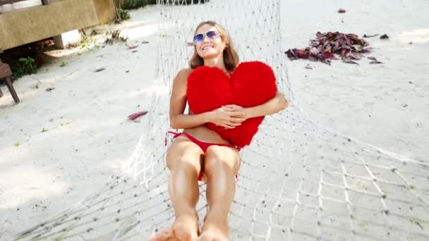 Donna in amaca sulla spiaggia tropicale dell'isola di Samui, Thailandia. Bella ragazza yuong posa con giocattolo sulla spiaggia. Bikini rosso e occhiali da sole . — Video Stock