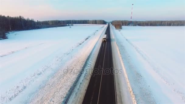 Muitos caminhões dirigem na estrada da neve ao pôr do sol . — Vídeo de Stock