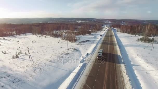 De nombreux camions roulent sur l'autoroute des neiges au coucher du soleil . — Video