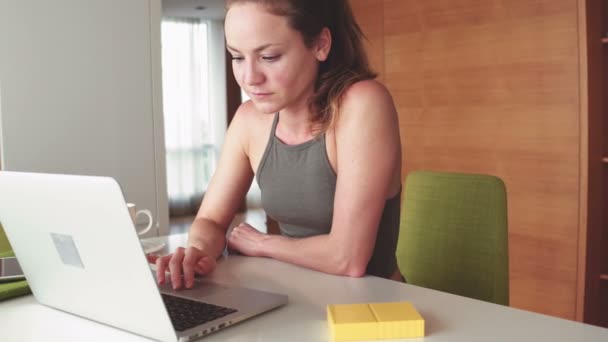 Mulher loira bonita com um computador portátil em casa — Vídeo de Stock