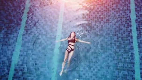 Horní pohled letecké fotografie svůdného sexy modelky v černých plavkách se těší relaxaci v hotelovém bazénu. Úžasná módní žena v bikinách s luxusním wellness odpočinkem — Stock video