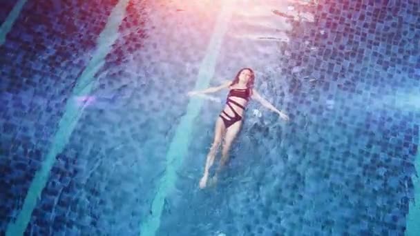 La photo aérienne d'un séduisant modèle sexy en maillot de bain noir profite de la détente dans la piscine de l'hôtel. Femme de mode incroyable en bikini ayant un repos spa de luxe — Video