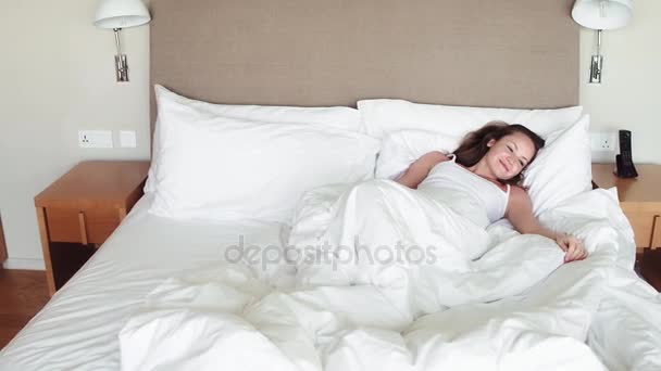 Νεαρή γυναίκα outstretching αγκαλιά καθιστή στο κρεβάτι μετά από καλό νυχτερινό ύπνο, απρόθυμοι να σηκωθεί και να αφήσει την άνετη φωλιά, Μπαίνοντας μια μέρα χαρούμενος και χαλαρός, έτοιμος για παραγωγική εργασία. Πίσω όψη — Αρχείο Βίντεο