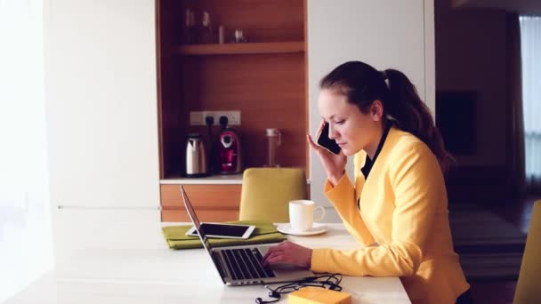 Genç güzel kadın çalışma Her ev ofis bilgisayarı ve telefonla konuşurken. — Stok video