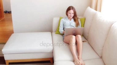 Kanepede oturan ve bilgisayarına bir şeyler yazan bir kız. Günbatımında dizüstü bilgisayar kullanan genç bir kadın..