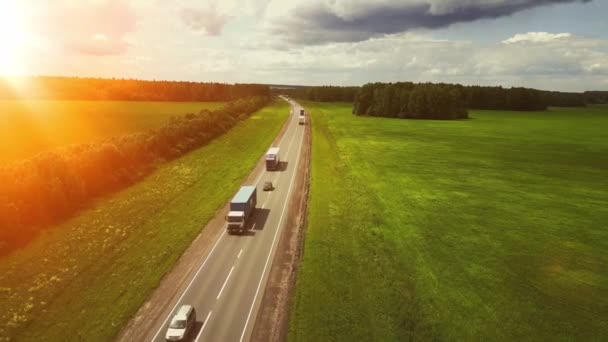 Beau paysage avec un tour sur l'autoroute les camions et quelques voitures au coucher du soleil. vue aérienne — Video