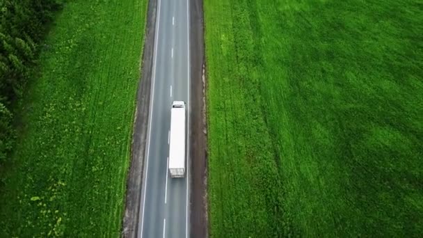 Delivery trucks driving towards the sun. Aerial view f green fields snd trucks — Stock Video